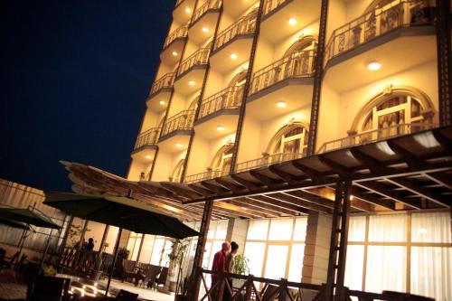 deux personnes debout devant un bâtiment la nuit dans l'établissement Venetian Hotel, à Addis-Abeba