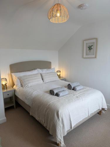 ein Schlafzimmer mit einem weißen Bett mit Handtüchern darauf in der Unterkunft New renovated beach front cottage in Mousehole