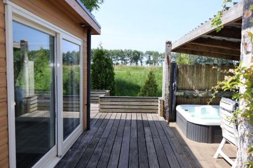 a wooden deck with a tub and a window at Chalet 30 met jacuzzi in Sint Annaland