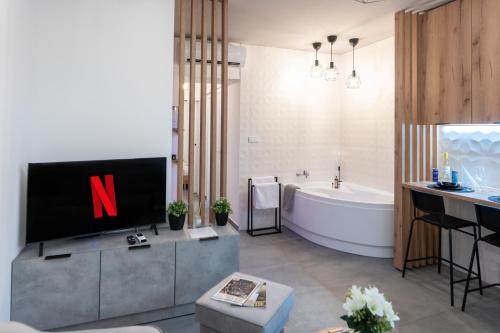 a bathroom with a tv and a tub and a sink at AApartman Wellness in Pécs