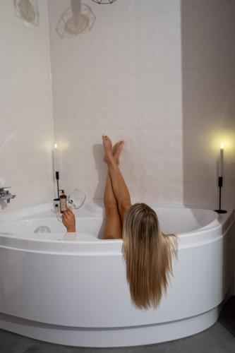 a woman sitting in a bath tub with her legs up at AApartman Wellness in Pécs