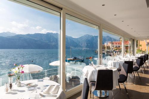 a restaurant with a view of the water and mountains at Hotel Vega in Malcesine