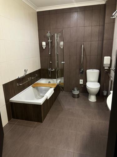 a bathroom with a tub and a toilet and a sink at Optima Collection Troitska in Dnipro