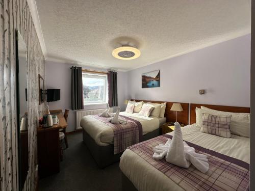 a hotel room with two beds with towels on them at Guisachan Guesthouse in Fort William