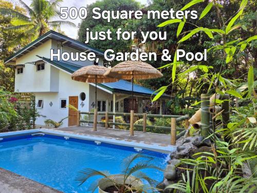 a villa with a swimming pool in front of a house at Amazing Ocean View Treehouse & Pool in Puerto Princesa City