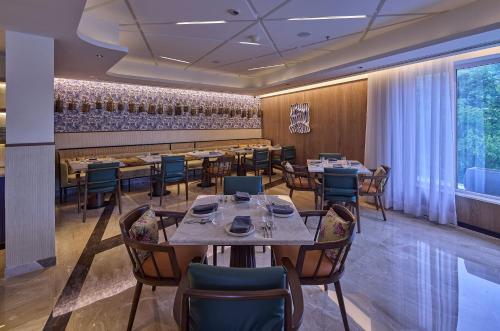 a restaurant with tables and chairs and a bar at ICONIQA Hotel Mumbai International Airport in Mumbai