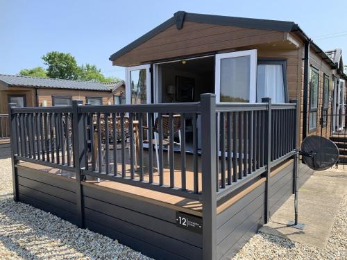 a tiny house with a porch and a fence at Longdon Lodge in Evesham