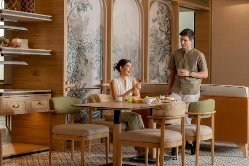 a man and a woman sitting at a table in a kitchen at Staybridge Suites Bangkok Sukhumvit by IHG in Bangkok