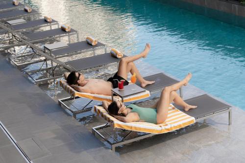 a group of people laying on lounge chairs in a pool at Staybridge Suites Bangkok Sukhumvit by IHG in Bangkok
