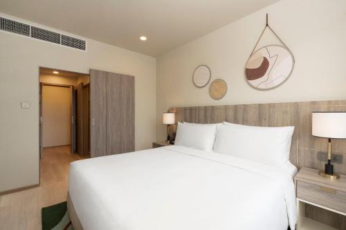a bedroom with a large white bed and two clocks on the wall at Staybridge Suites Bangkok Sukhumvit by IHG in Bangkok