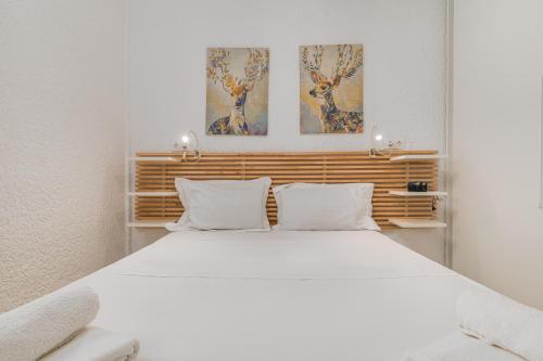 a bedroom with a white bed with two paintings on the wall at The Little Loft in Pefkochori
