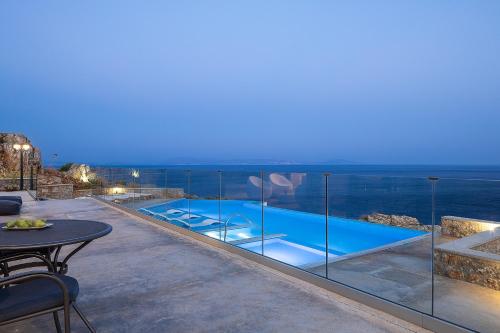 a villa with a swimming pool at night at Seafront elegant villas, with infinity pools & devine views! in Agios Pavlos