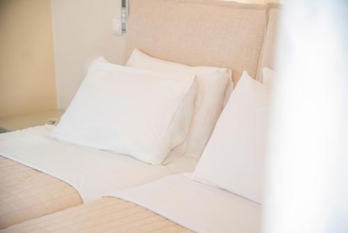 a pile of white pillows sitting on a bed at Princess Hotel in Lassi