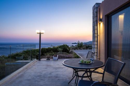 a table and chairs on a patio with a view of the ocean at Seafront elegant villas, with infinity pools & devine views! in Agios Pavlos