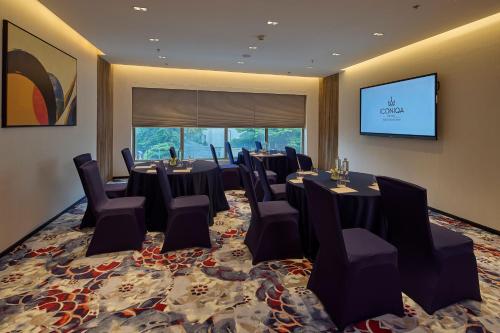 a conference room with tables and chairs and a screen at ICONIQA Hotel Mumbai International Airport in Mumbai