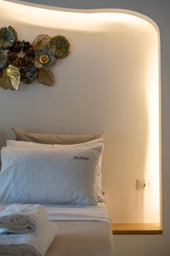 a bed with a white pillow and flowers on the wall at Meltemi Marmaras in Neos Marmaras