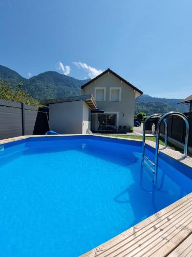 une grande piscine bleue avec des montagnes en arrière-plan dans l'établissement Évasion et confort maison 8 couchages avec piscine, à Marlens