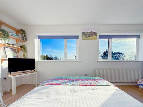 a bedroom with a bed and two windows at Glastonbury Studio- amazing views and Free Parking in Glastonbury