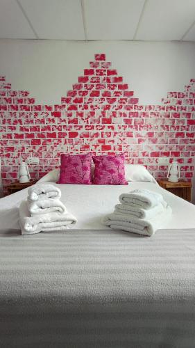 a bed with towels on it with a brick wall at Casa rural Julia in Olleros de Tera