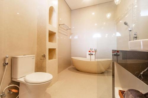 a bathroom with a toilet and a bath tub at Villa Amaia Canggu in Kerobokan