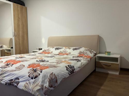 a bed with a floral comforter in a bedroom at Cozy Gem Cluj meets Nature in Floreşti
