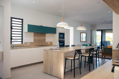 a kitchen with white cabinets and a island with bar stools at Blue Nest Luxury Penthouse in Blue Bay