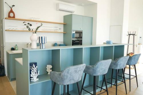 une cuisine avec des placards bleus et des tabourets de bar dans l'établissement Loft vue mer - Angoulins - Villa Oasis, à Angoulins-sur-Mer