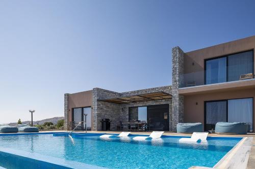 a villa with a swimming pool in front of a house at Seafront elegant villas, with infinity pools & devine views! in Agios Pavlos