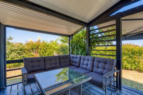 a screened in porch with a couch and a table at Chalet de la Grenatière in Pomérols