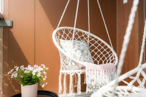 a swing chair on a porch with flowers at Wallesmanni - Nokia Arena prime location apartments by Come in! in Tampere