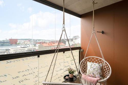 a hanging chair in a room with a large window at Wallesmanni - Nokia Arena prime location apartments by Come in! in Tampere
