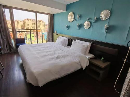 a bedroom with a large bed with a blue wall at Crystal Orange Shanghai Lingang Ocean Park Hotel in Nianbalian