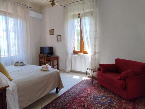 a bedroom with a bed and a red couch at MARIA HOLIDAY HOMES La Pineta di Sinalunga in Sinalunga