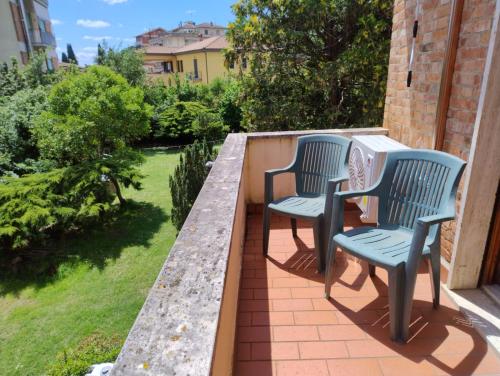 two chairs sitting on a balcony with a garden at MARIA HOLIDAY HOMES La Pineta di Sinalunga in Sinalunga