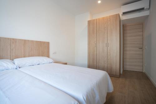 a bedroom with a white bed and a wooden cabinet at LETS HOLIDAYS Centric & Near the Sea Victoria apartment 3 in Tossa de Mar