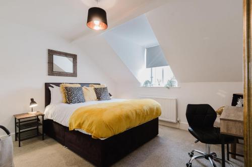 a bedroom with a bed with a yellow blanket on it at Licata's Apartment in Cirencester