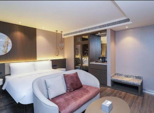 a bedroom with a bed and a couch and a table at Crystal Orange Shanghai Lingang Ocean Park Hotel in Nianbalian