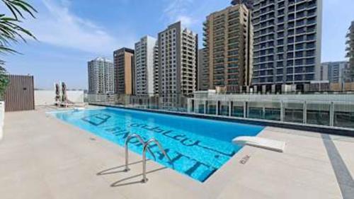 uma grande piscina em frente a alguns edifícios altos em Spacious Apartment for 4 in JVC no Dubai