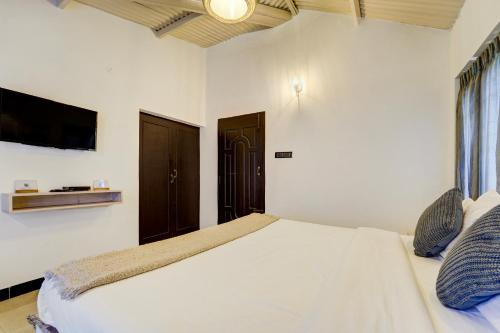 a bedroom with a white bed and a tv at Garden Haven 3 BHK Villa with Balcony and Verandah Escape in Kotagiri