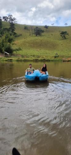 two people are riding on a blue raft in the water at Refúgio dos pinhais in Sapucaí-Mirim