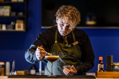 a man wearing an apron making a drink at a counter at Comwell Aarhus Dolce by Wyndham in Aarhus