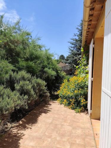 a walkway next to a house with flowers at Maison conviviale avec jardin à Bras-d'Asse in Bras-dʼAsse