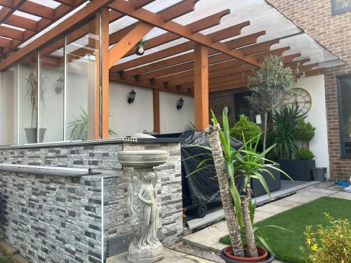 a patio with a stone wall and a wooden pergola at Olive Garden House in Manor