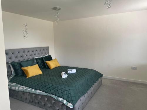 1 dormitorio con 1 cama con sábanas verdes y almohadas amarillas en Olive Garden House, en Manor