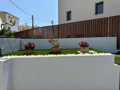 a white fence with three potted plants on it at Evdokia Suites in Gouves