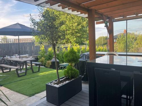 a patio with a table and a tree in a garden at Olive Garden House in Manor