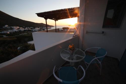 a table and chairs on a balcony with the sunset at Casaprimavera in Katapola