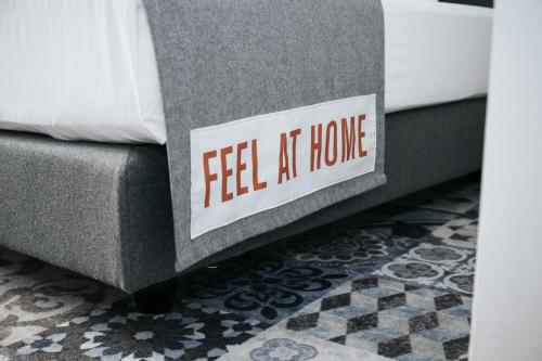 a sign that says feel at home sitting on a bed at Hotel Berliner Hof by Coffee Fellows Hotels in Kiel