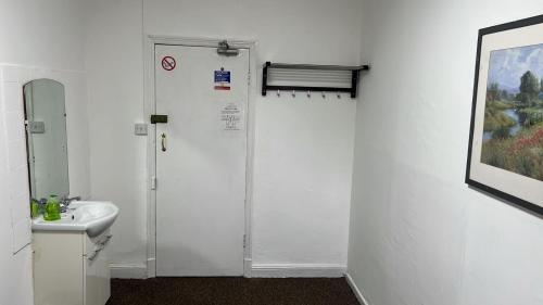 a white bathroom with a sink and a shower at Campbells Guest House in Leicester
