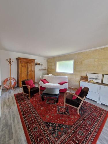a living room with a bed and a red rug at La maison des vendangeurs in Libourne
